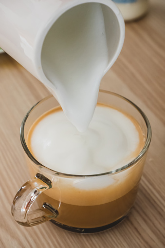 The milk foam is pouring into the coffee.