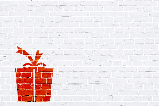A white, light gray colored brick wall with rectangular blocks, textured grungy backgrounds. No text. No people, copy space, copyspace. Vector Xmas background. White colour vintage wall paper with an Xmas present to the right in empty grunge the frame. The gift is wrapped up and tied by ribbon tied into a bow on the top.  Apt for New Year, New Year's eve, birthday, Xmas party gifts presents wallpaper.
