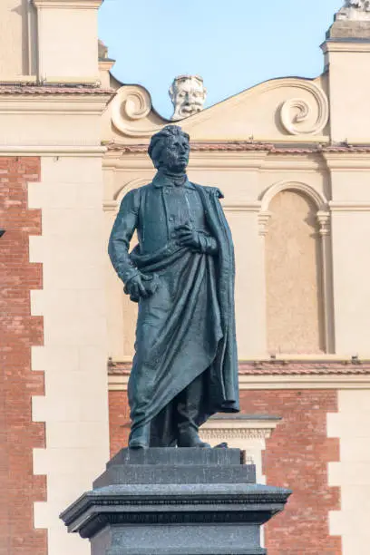 Photo of Close-up of Adam Mickiewicz Monument with Cloth Hall in background in Krakow, Poland.