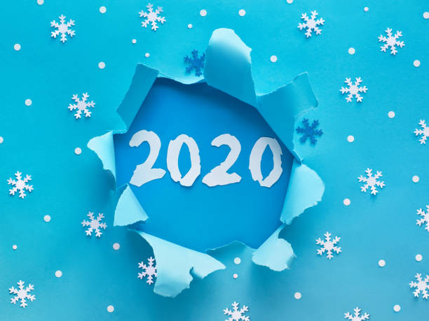 istock Blue paper flat lay with snowflakes and number 2020 inside ripped hole 1179208859
