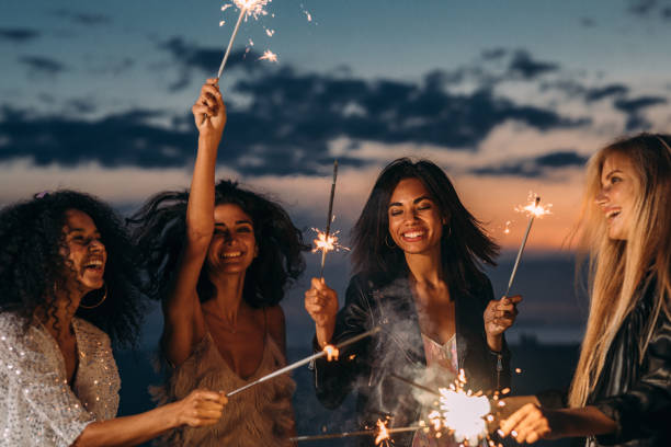 istock Four happy women celebrating at sunset with sparklers 1179210932