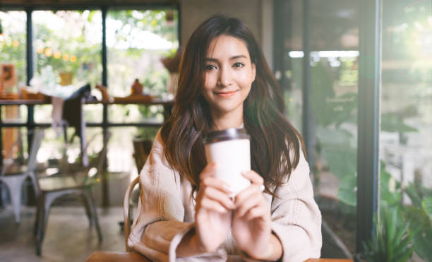 femme asiatique de verticale appréciant la tasse de café un dans le café - coffee shop coffee break coffee cup holding photos et images de collection