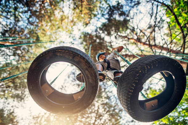 Little boy walking on tyres at the ropes course Little boy walking on hanging tyres in ropes course in adventure park. 
Sunny summer day.
Nikon D850 canopy tour photos stock pictures, royalty-free photos & images