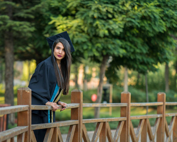 mujer tomando un montón de diferentes fotos de graduación en un hermoso parque botánico. - poses para fotos de graduación fotografías e imágenes de stock