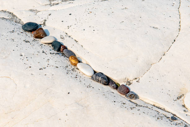 Small beach pebbles in a row on a rocky white surface.