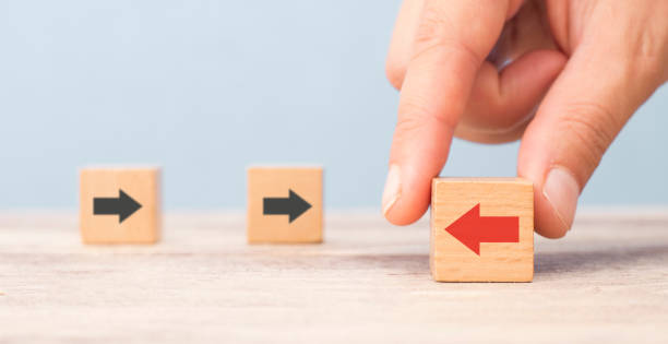 istock different thinking concept. Hand chooses red arrow facing opposite direction with black arrow 1179237697