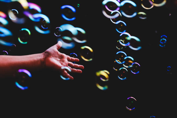 istock Hand trying to catch colorful bubbles over dark background 1179240242