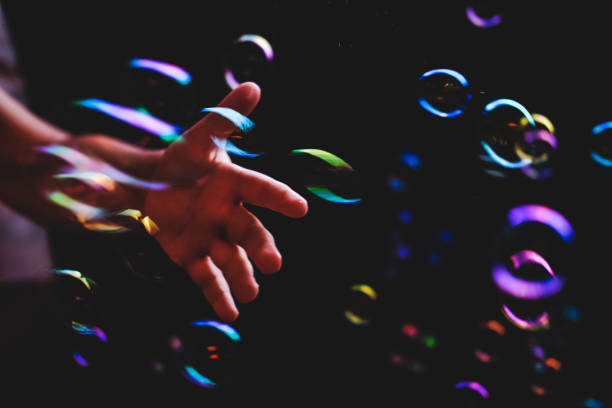 istock Hand trying to catch colorful bubbles over dark background 1179240286