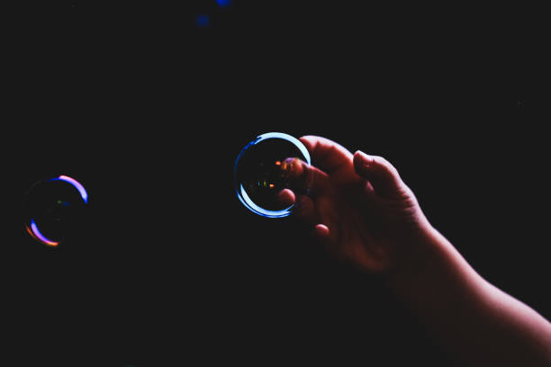 istock Hand trying to catch colorful bubbles over dark background 1179240312