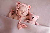 Cute newborn baby girl sleeping with teddy bear.