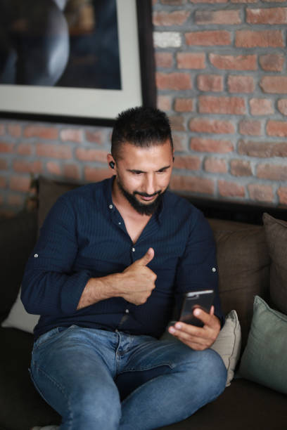 istock mature man talking on mobile phone with headphones while sitting on sofa in cafe 1179245309