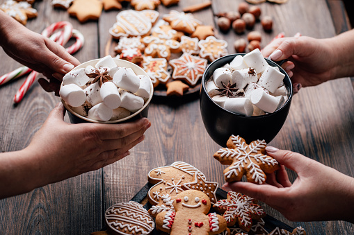 Christmas and New Year holidays, family weekend activities, celebration mood. Friends eating festive sweets with hot chocolate. Winter warming concept and friendly atmosphere