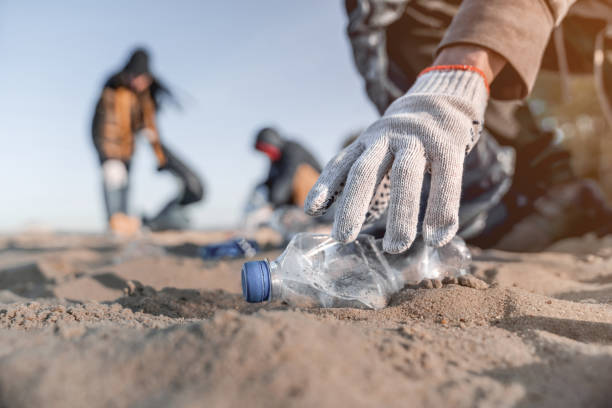 volontario che raccoglie spazzatura sulla spiaggia. concetto di ecologia - spring cleaning foto e immagini stock