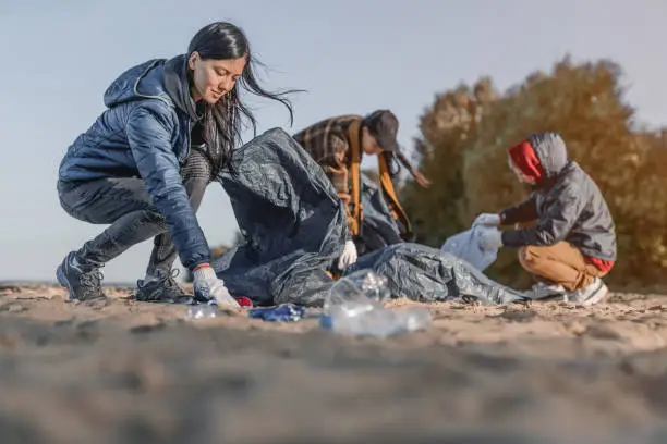 Photo of Group of young people cleaning beach area