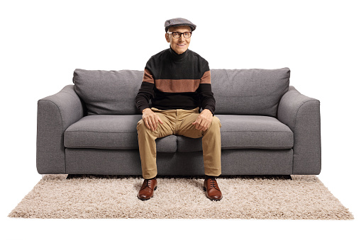 Elderly man sitting on a sofa and smiling isolated on white background