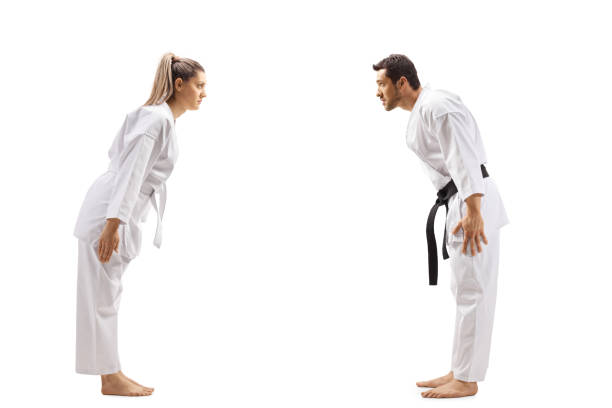 femme avec la ceinture blanche dans le karaté et un homme avec la ceinture noire s'inclinant l'un à l'autre - martial arts women tae kwon do black belt photos et images de collection