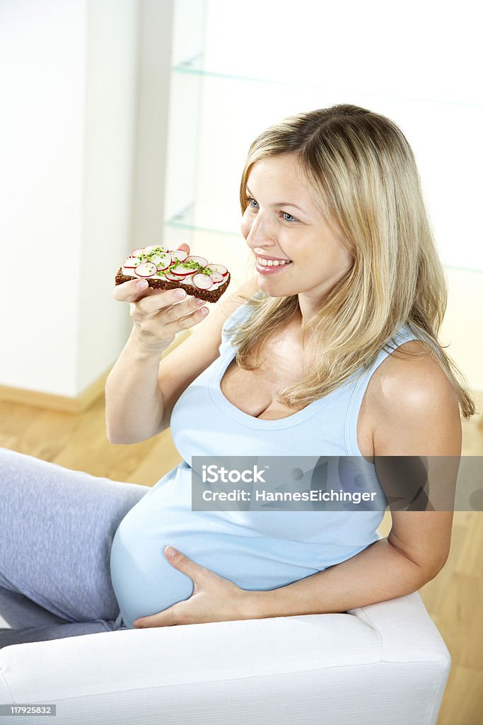 Giovane donna incinta mangia Pane integrale - Foto stock royalty-free di Adulto