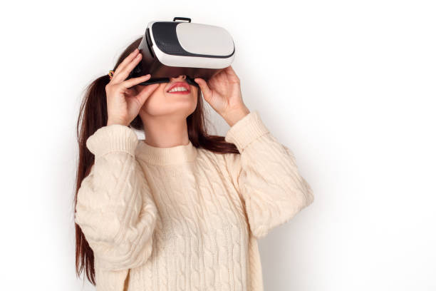 istock Young girl with two ponytails in virtual reality headset studio standing isolated on white watching video cheerful 1179260540