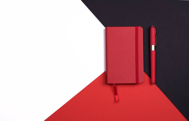 istock red Notepad with pen on red, white and black background. Top view. 1179261141