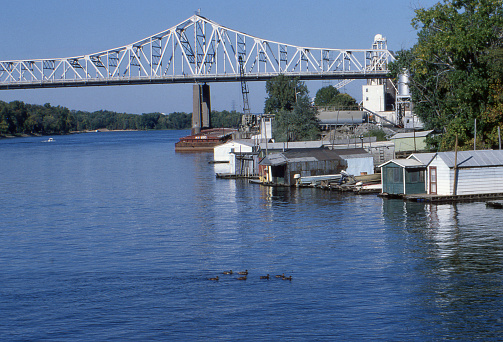 Mississippi River at La Crosse, Wisconsin, USA. Mississippi River Bridge, also known as Cass Street Bridge, before construction of additional span in 2004. Cantilever truss construction. Houses built over water, grain barge. 1979. Ektachrome scanned film with grain.