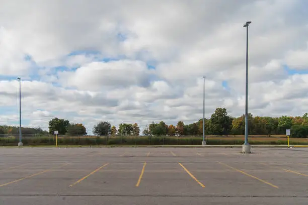 Photo of Empty parking lot with a forest in the background and partly cloudy sky