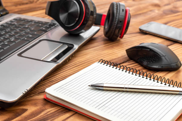 istock Wooden desk with blank notepad, laptop, smartphone, computer mouse and headphones. 1179291499