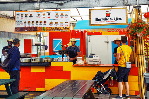 Montreal, Canada, June, 2018: Staff taking orders from customers behind the stand at mermite sul feu island of reunion fast food restaurant in Atwater market, Montreal, Canada.
