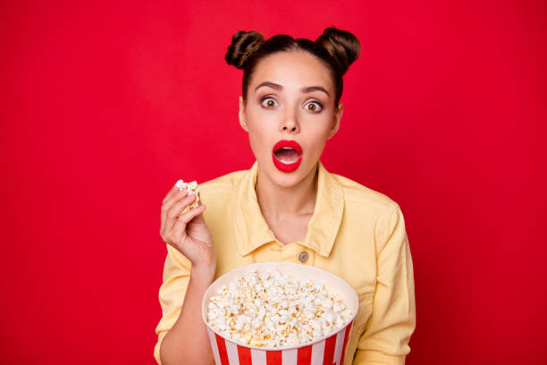 Pretty lady holding popcorn container watching horror movie wear casual outfit isolated red background Pretty lady holding popcorn, container watching horror movie wear casual outfit isolated red background topknot stock pictures, royalty-free photos & images