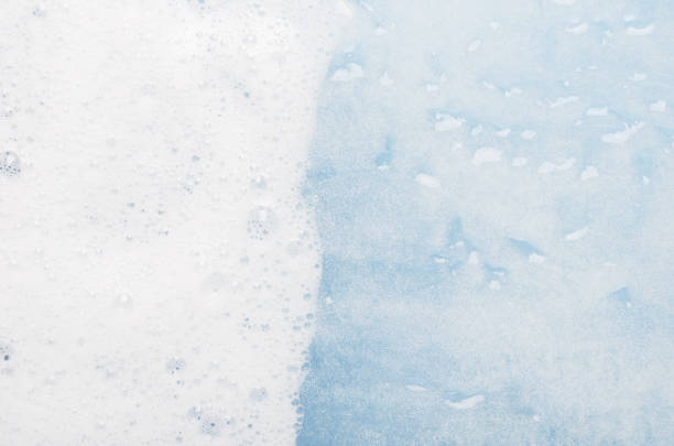 istock White foam on blue water top view background. Soapy liquid with white bubbles macro. Mousse texture, snow-white froth. Shower gel foam closeup. Household washing liquid, detergent dissolving in water 1179294927
