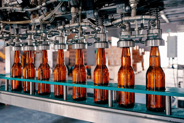 riempimento bottiglie di birra sul nastro trasportatore nello stabilimento del birrificio - cibo e bevande foto e immagini stock
