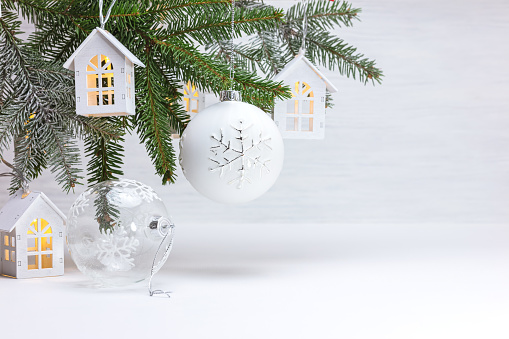 beautiful new year holiday background with christmas tree branch, wooden decorative toy houses garland and glass balls