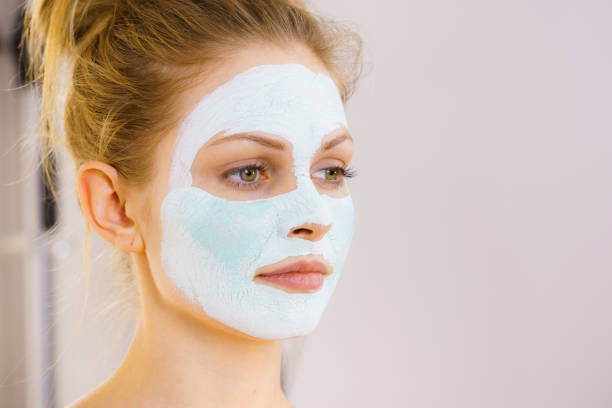 istock Girl with white green mud mask on face 1179320749