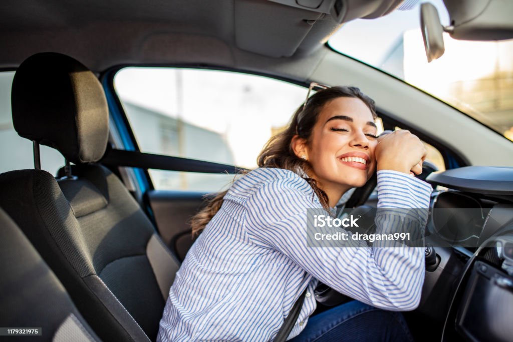 Junge und fröhliche Frau genießt neues Auto umarmen Lenkrad sitzen im Inneren - Lizenzfrei Auto Stock-Foto