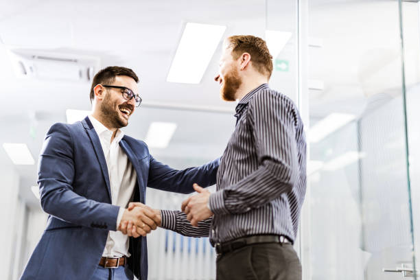 istock Happy male entrepreneurs talking while shaking hands in a hallway. 1179326186