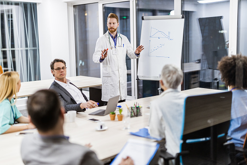 Young medical experts leading a presentation with businessmen and his colleagues in the hospital.