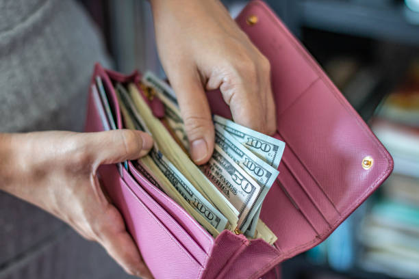 istock Woman taking out US dollar bills from her pocket wallet (depth of field photography). 1179327181