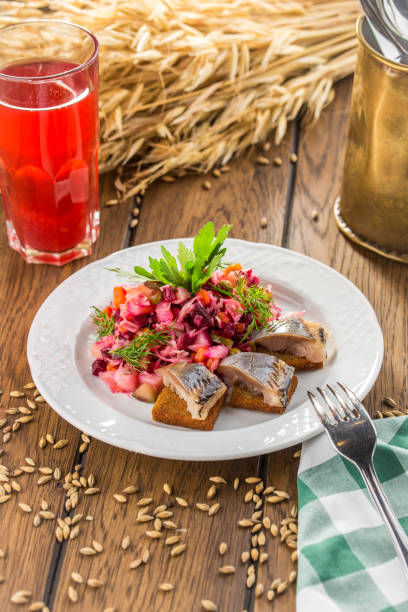 Sandwiches with herring and beetroot salad on wooden table side view