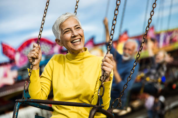 istock Happy senior woman having fun while riding on chain swing at amusement park. 1179329568