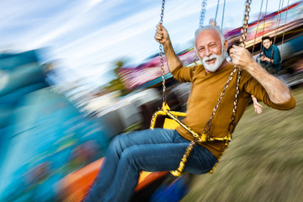istock Happy mature man having fun on a chain swing ride at amusement park. 1179330333