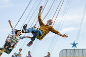 Carefree people having fun on chain swing ride in amusement park.