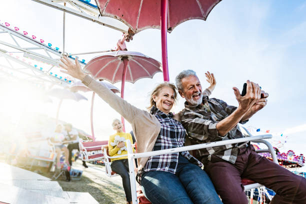 Happy senior couple taking a selfie during amusement park ride.