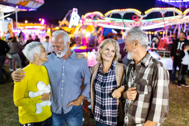 istock Happy mature couples talking at amusement park by night. 1179334468