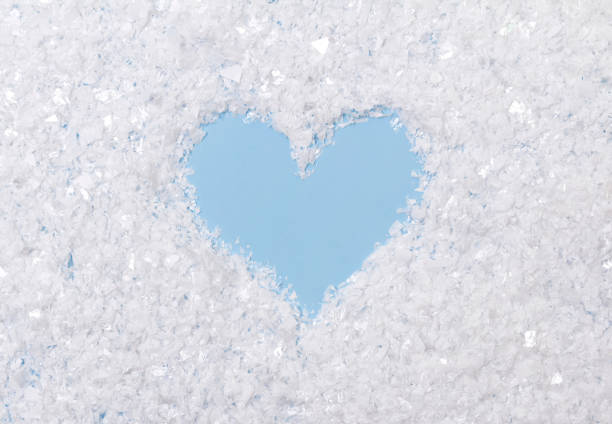 istock White fluffy artificial snow on blue background with heart 1179334761