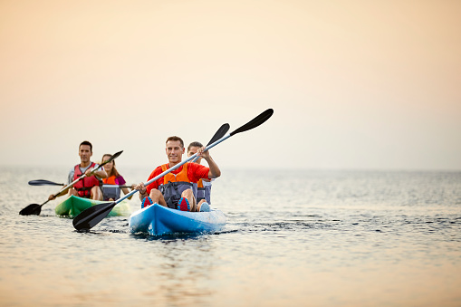 Couples kayaking together on river. Happy males and females are enjoying water sport in summer. They are enjoying during vacations.