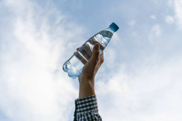 istock hand holding a plastic bottle with pure water against the sky 1179338578