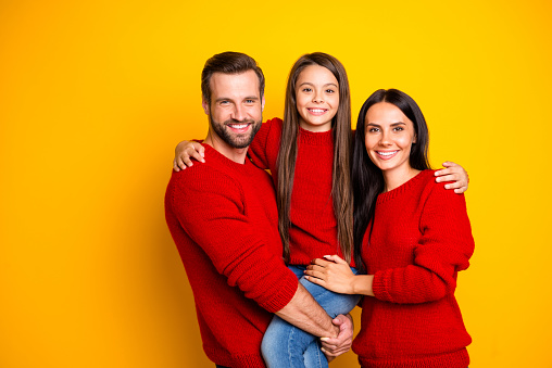 Photo of cheerful cute nice fascinating family embracing each other affectionately, wearing jeans denim hands holding enjoying joint leisure isolated over vivid color yellow background