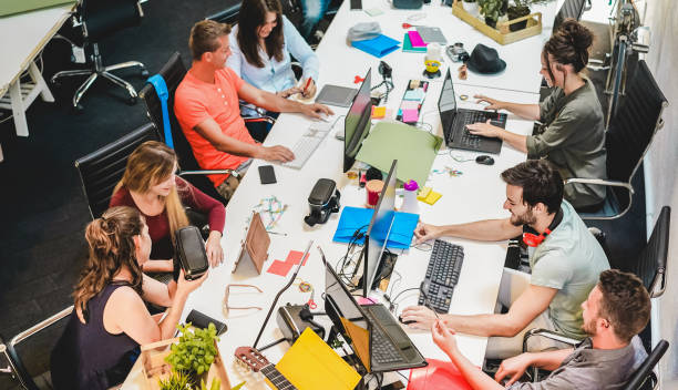 equipo de jóvenes compañeros de trabajo hablando durante la puesta en marcha - gente feliz planeando un nuevo proyecto en la oficina creativa del lugar de trabajo - tecnología, emprendedor, marketing y concepto - enfoque en el hombre izquierdo con auric - marketer fotografías e imágenes de stock