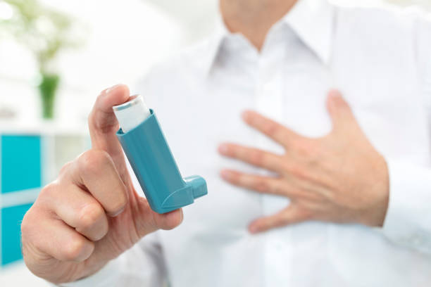 Man using blue asthma inhaler medication Man using blue asthma inhaler medication with breathing difficulties asthma inhaler stock pictures, royalty-free photos & images
