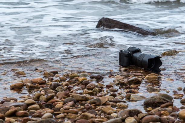 istock DSLR camera on stone beach wet from water sea wave 1179346563