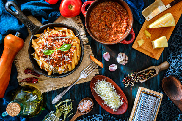 istock Penne with Bolognese sauce in serving size casserole with ingredients in rustic pots 1179347809